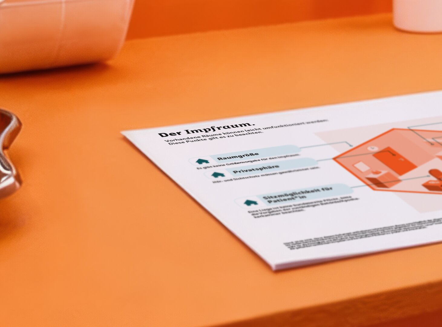 Eine ausgedruckte Infografik zum Thema Impfraum liegt auf auf dem Tisch im Büro einer Apotheke.