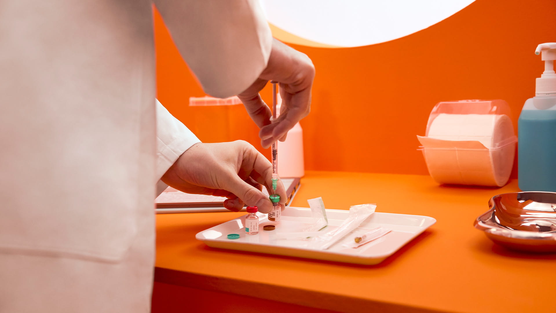 Hände eines Apothekers bereiten Spritze mit Impfung in stilisiertem Impfzimmer vor.